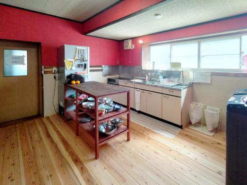 kuchnia z czerwonymi ścianami i drewnianą podłogą w obiekcie Amino Guesthouse Bench w mieście Kyotango
