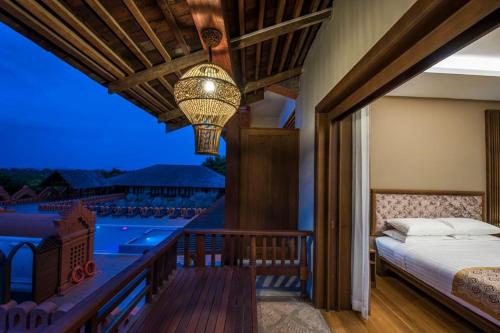 1 dormitorio con balcón con cama y lámpara de araña en Royal Palace Hotel en Nyoungoo