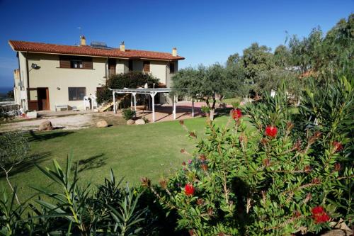 a house with a green yard with flowers in front of it at Agriturismo S'Ispiga in Cuglieri