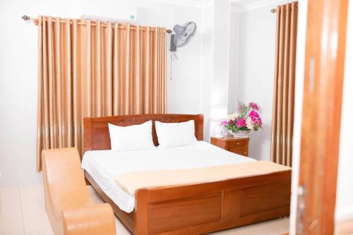 a bedroom with a wooden bed with white sheets and pillows at Thảo Nguyên Hotel in Vinh