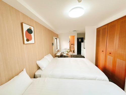 - 2 lits dans une chambre d'hôtel avec des draps blancs dans l'établissement Tutulu502, à Osaka