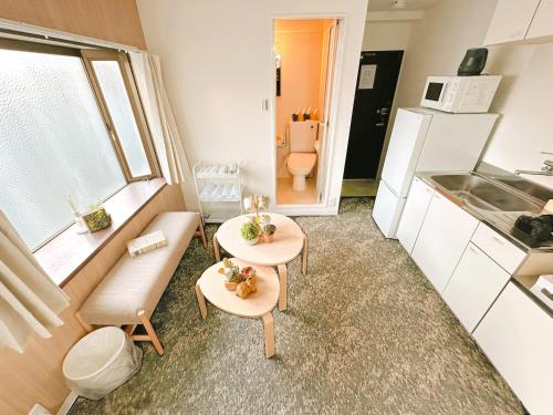 une petite chambre avec deux tables et une cuisine dans l'établissement Tutulu502, à Osaka