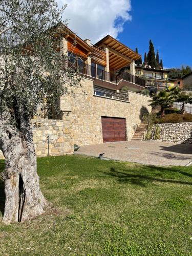 a stone house with a tree in the yard at Villa in Gardone Riviera zu vermieten in Gardone Riviera