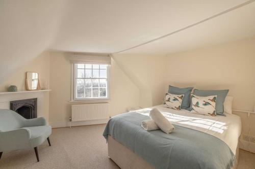 een witte slaapkamer met een bed en een stoel bij Impressive 3 Bed 2 Bath Townhouse in Windsor in Windsor