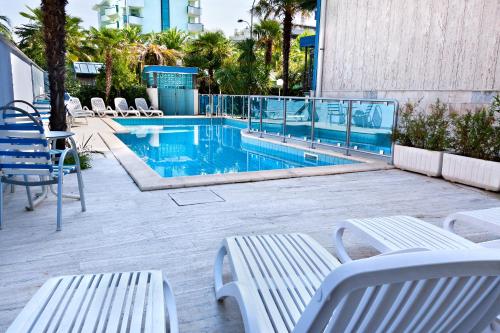 聖貝內代托德爾特龍托的住宿－Residence 7 Bello，一个带2个白色长椅和椅子的游泳池