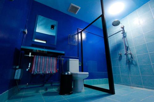 a blue bathroom with a toilet and a shower at Chez Pom in Chiang Mai