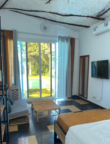 a bedroom with a bed and a couch and a tv at Keur Ama in Mbour