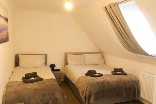 two beds in a small bedroom with a window at Entire Private House In Chalkwell (Southend) Amazing Sea Views in Southend-on-Sea