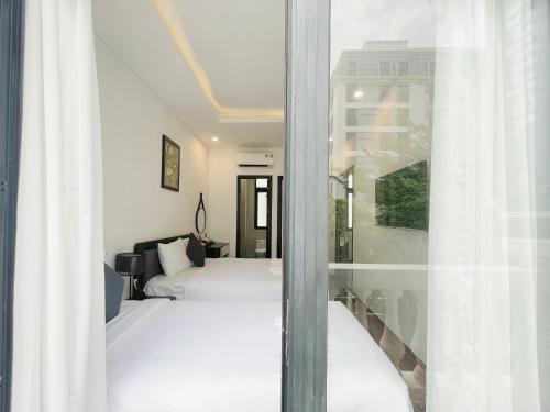 a hotel room with two beds and a window at Le Palmier Phu Quoc Hotel - Free Shuttle To Grand World in Phu Quoc