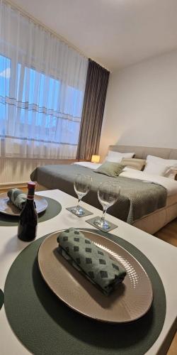 a living room with a table with glasses and a bed at Stadtoase Wels in Wels