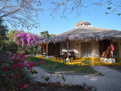 a house with a thatch roof and a garden at Antsanitia Resort in Mahajanga