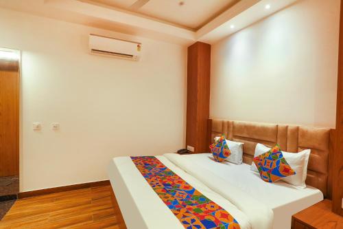 a bedroom with a bed with white sheets and colorful pillows at FabHotel Prime Swarn Bhoomi in Kānpur