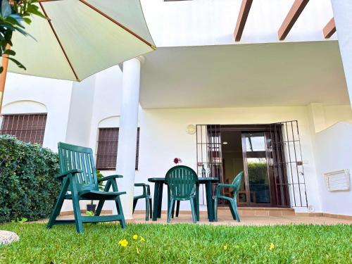 Un patio con sillas, una mesa y una sombrilla. en Coto de Sancti Petri, en Chiclana de la Frontera