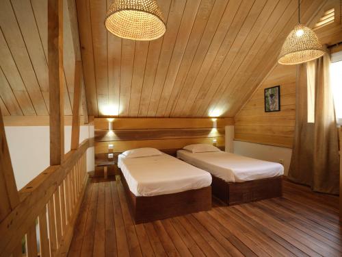 two beds in a room with wooden walls and wood floors at Antsanitia Resort in Mahajanga