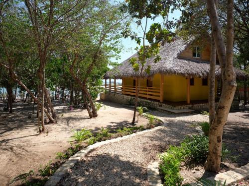 a yellow house with a thatched roof in a forest at Antsanitia Resort in Mahajanga