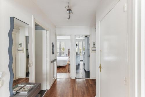 a white room with a hallway with a bed and a mirror at Charme et authenticité à Montmartre by Weekome in Paris