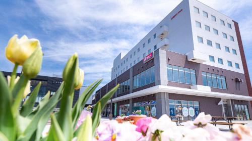 a building with pink flowers in front of it at Hotel La'gent Plaza Hakodate Hokuto in Hokuto