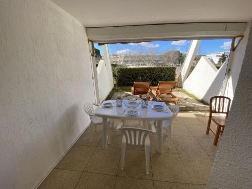 une table blanche et des chaises sur une terrasse dans l'établissement Sol-y-Days Flamants roses, appartement rez-de-jardin avec piscine, à La Grande Motte