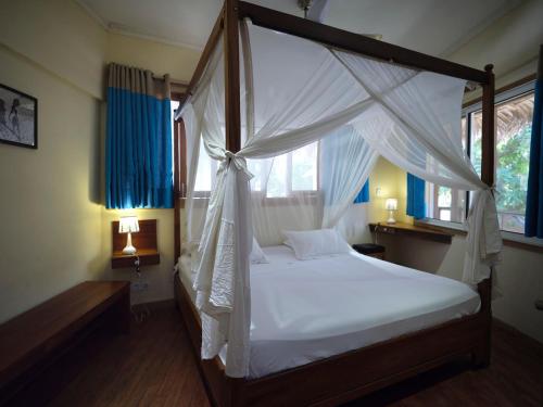 a bedroom with a canopy bed with white sheets at Antsanitia Resort in Mahajanga