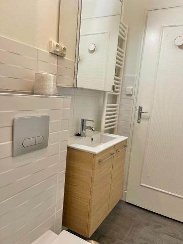 - une petite salle de bains blanche avec lavabo et porte dans l'établissement Hôtel de Ville - au cœur du centre de Bourges 1 chambre, à Bourges
