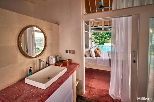 a bathroom with a sink and a bed and a mirror at Mandala The Bay in Nusa Lembongan