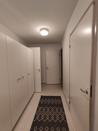 un pasillo con armarios blancos y una alfombra negra en Ketola Apartments Reisjärvi, en Reisjärvi