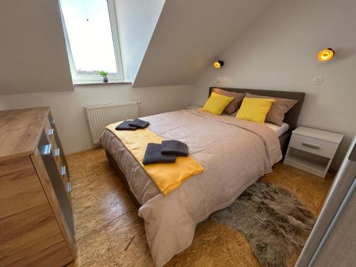 Un dormitorio con una cama con almohadas amarillas y una ventana en Apartment A1 en Liubliana