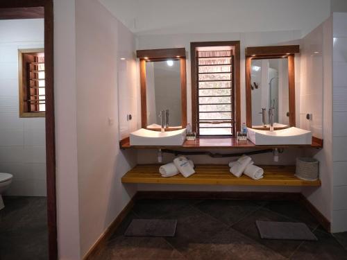 a bathroom with two sinks and two mirrors at Antsanitia Resort in Mahajanga