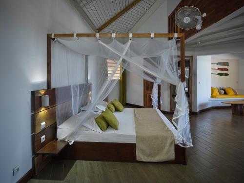 a bedroom with a canopy bed with green pillows at Antsanitia Resort in Mahajanga