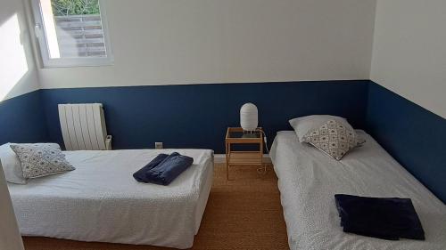 une chambre avec deux lits et un mur bleu dans l'établissement AU PARADIS DE BB, à Biéville-Beuville