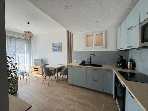 une cuisine avec des armoires blanches et une table avec des chaises dans l'établissement Superbe appartement 4 personnes les pieds dans l'eau, à Saint-Mandrier-sur-Mer