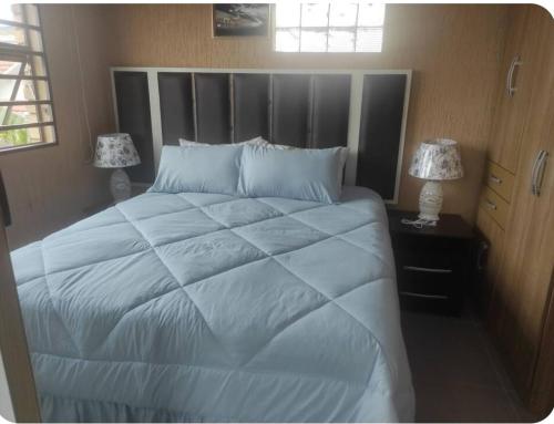 a bedroom with a large white bed with two lamps at Brand new crane Apartments no 9 in Lenasia
