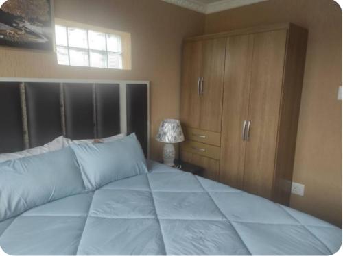 a bedroom with a large bed and a cabinet at Brand new crane Apartments no 9 in Lenasia