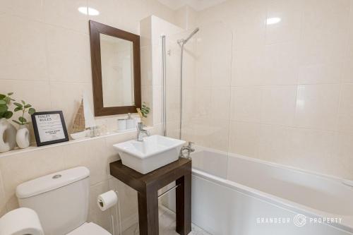 a bathroom with a sink and a toilet and a bath tub at The Catalina Breeze by Grandeur Property in Poole