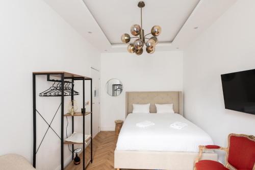 um quarto com uma cama branca e uma televisão em Paris Eiffel em Paris