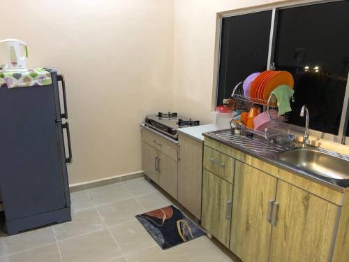 eine Küche mit einer Spüle und einem Kühlschrank in der Unterkunft HOMESTAY PERLIS MURAH in Arau