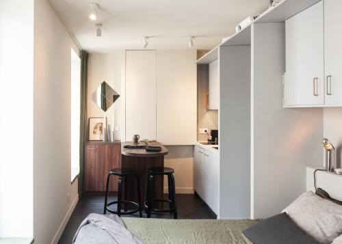 - une petite cuisine avec des placards blancs et une table dans la chambre dans l'établissement Tiny House Paris Nord, à Paris