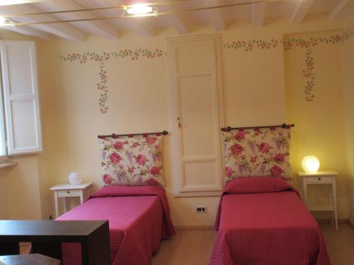 ルッカにあるMimì Apartmentの赤いシーツと花が壁に飾られた客室内のベッド2台