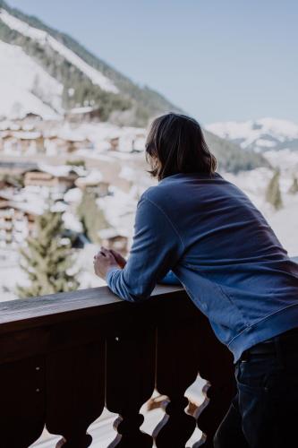 a person standing on a balcony looking out at the snow at Hotel Sonnegg in Saalbach Hinterglemm