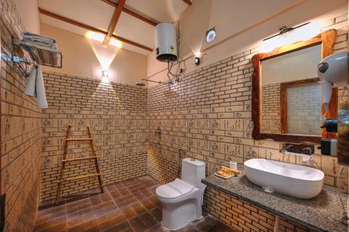 a bathroom with a sink and a toilet and a mirror at Bagh Serai - Rustic Cottage with Private Pool in Sawāi Mādhopur