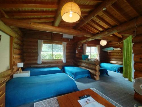 Habitación con camas azules en una cabaña de madera. en Pension Shishikui, en Shishikui
