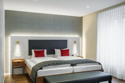 a bedroom with a large white bed with red pillows at Hotel Du Nord in Interlaken