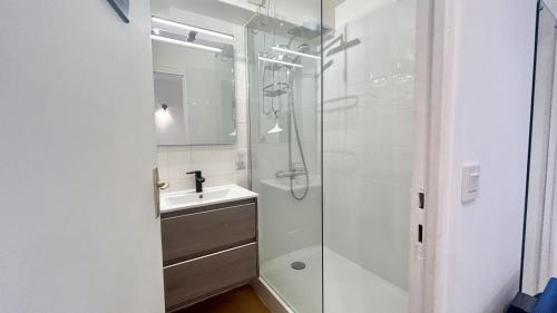 een witte badkamer met een wastafel en een douche bij Les Tamaris in Le Crotoy