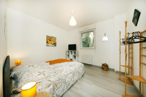 a white bedroom with a bed and a television at L'Océraline - Maison avec jardin et wifi in La Lucerne-dʼOutremer
