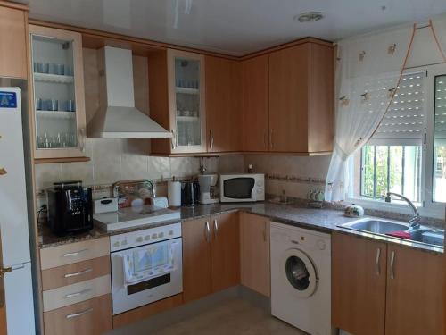 een keuken met houten kasten en een wasmachine bij Apartment mit Bergblickterrasse bei Lloret de Mar in Vidreres