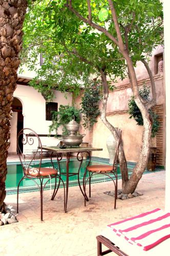 a table and chairs sitting under a tree at Riad Palmier in Marrakech