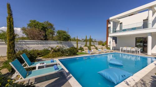 a swimming pool with chairs and a house at Diamond villas in Protaras