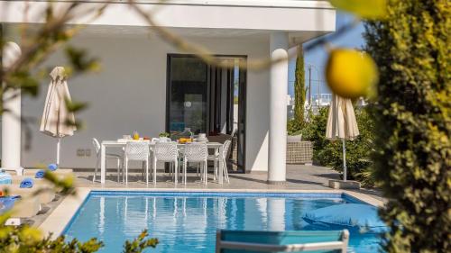 a pool with a table and chairs next to a house at Diamond villas in Protaras