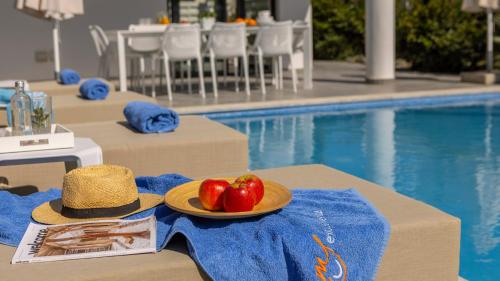 a hat and a plate of fruit on a table by a pool at Diamond villas in Protaras