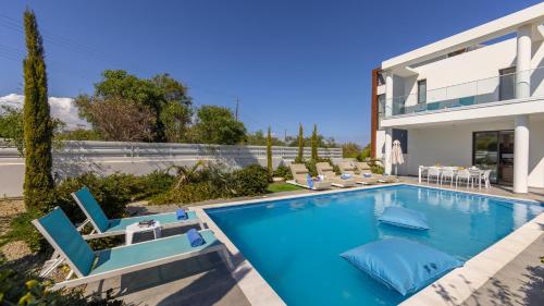 a swimming pool with chairs and a house at Diamond villas in Protaras